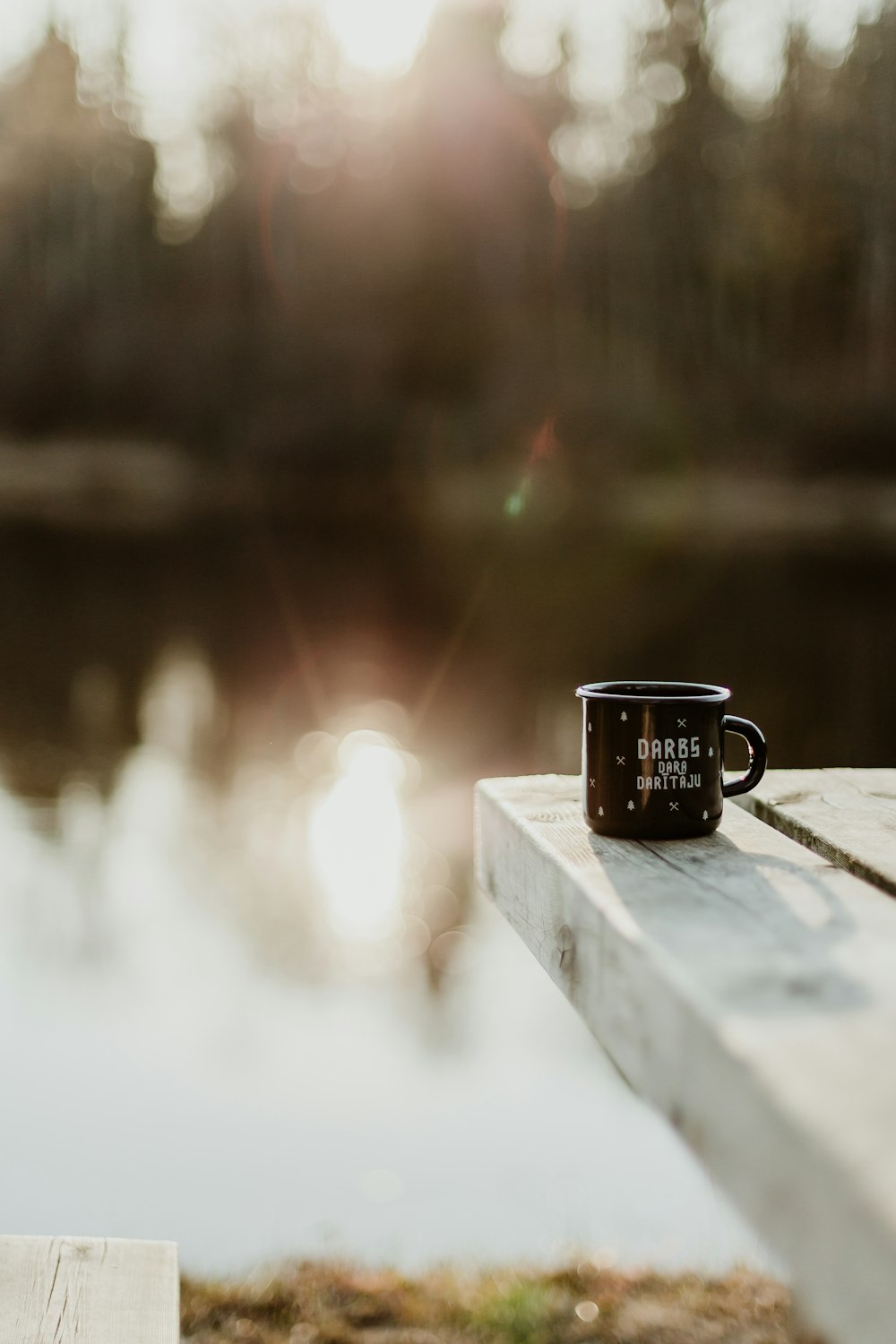 tazza nera sul molo vicino al lago