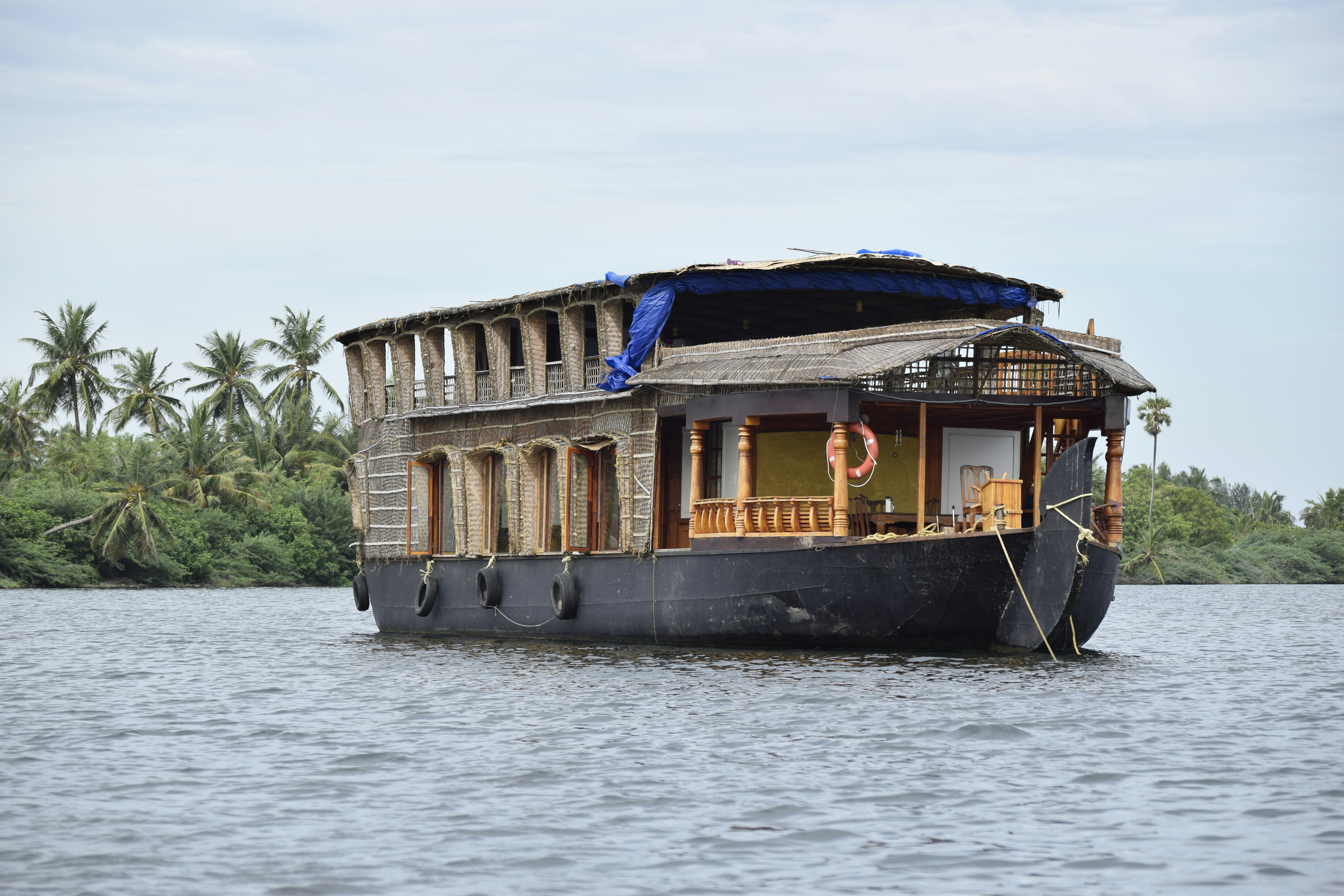 Lush green backwaters with traditional wooden houseboat gliding through calm tropical waterways, vibrant greenery