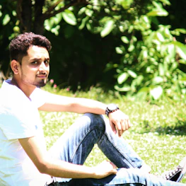 A relaxed person wearing a lentoviva tee, sitting in a sunlit park.