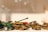 A collection of toy military vehicles, including tanks and trucks, is arranged in a display. The toys have a vintage look, with some painted in green and others in a muted gold color. The lighting creates a warm, nostalgic ambiance, highlighting the intricate details of the small models.