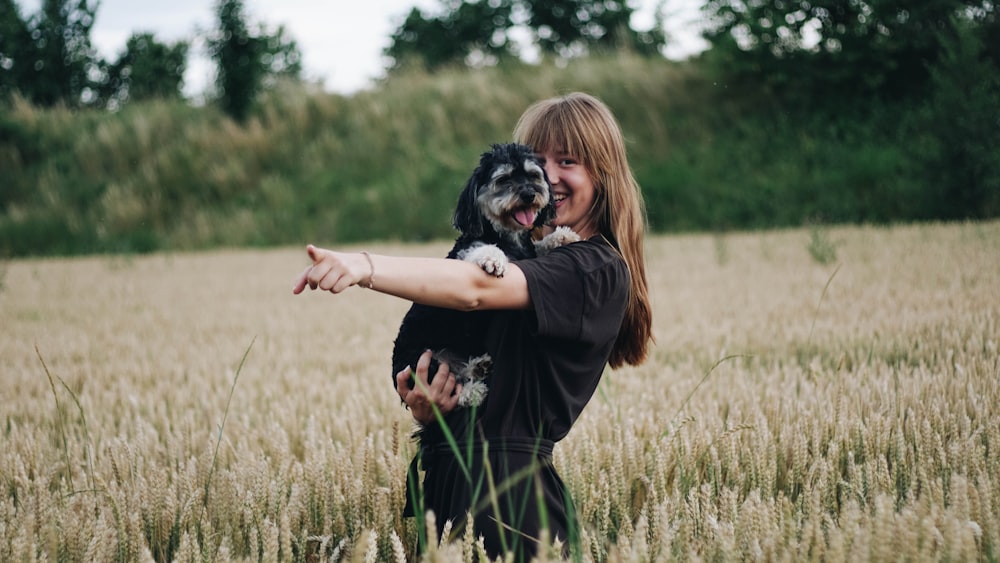 woman standing on grass field while holds dog
