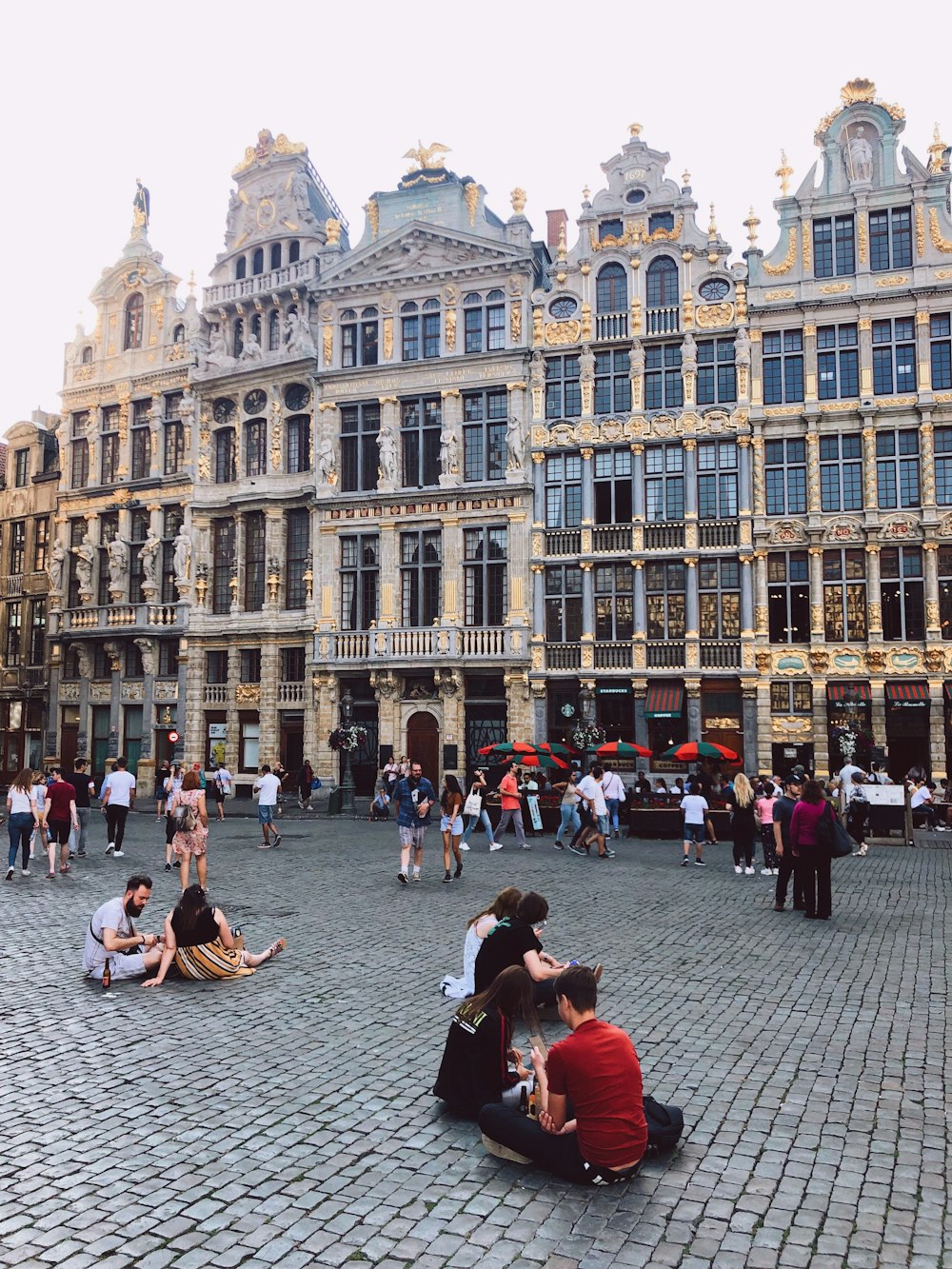 people sitting and standing beside high buildings during daytime