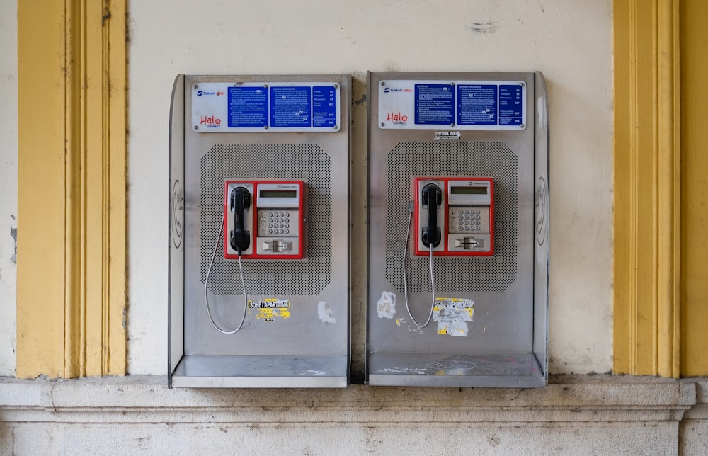 two gray-and-red coin operated telephone machine