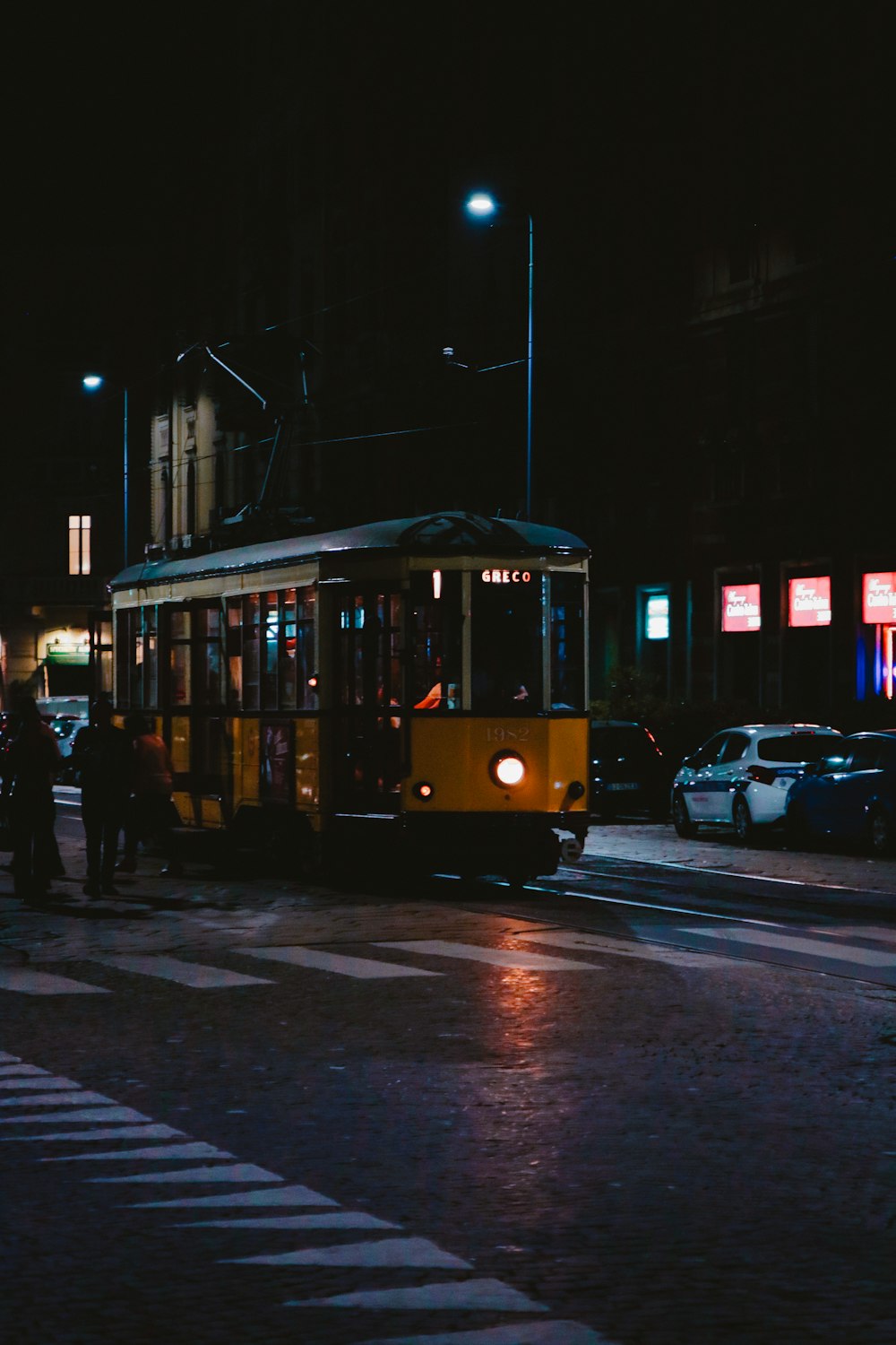 夜間の黄色い電車のそばに立つ人々