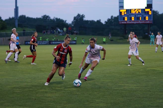 An intense soccer match with players chasing a ball near the goal.