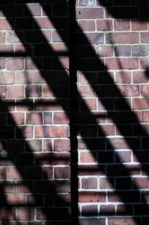A partially built brick wall with sunlight casting shadows.
