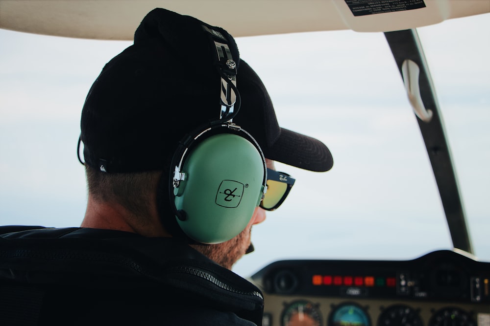 man wearing black top and black baseball cap using green headset