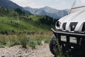 Jeep offroad crossing rocky terrain with lush green mountains in the background