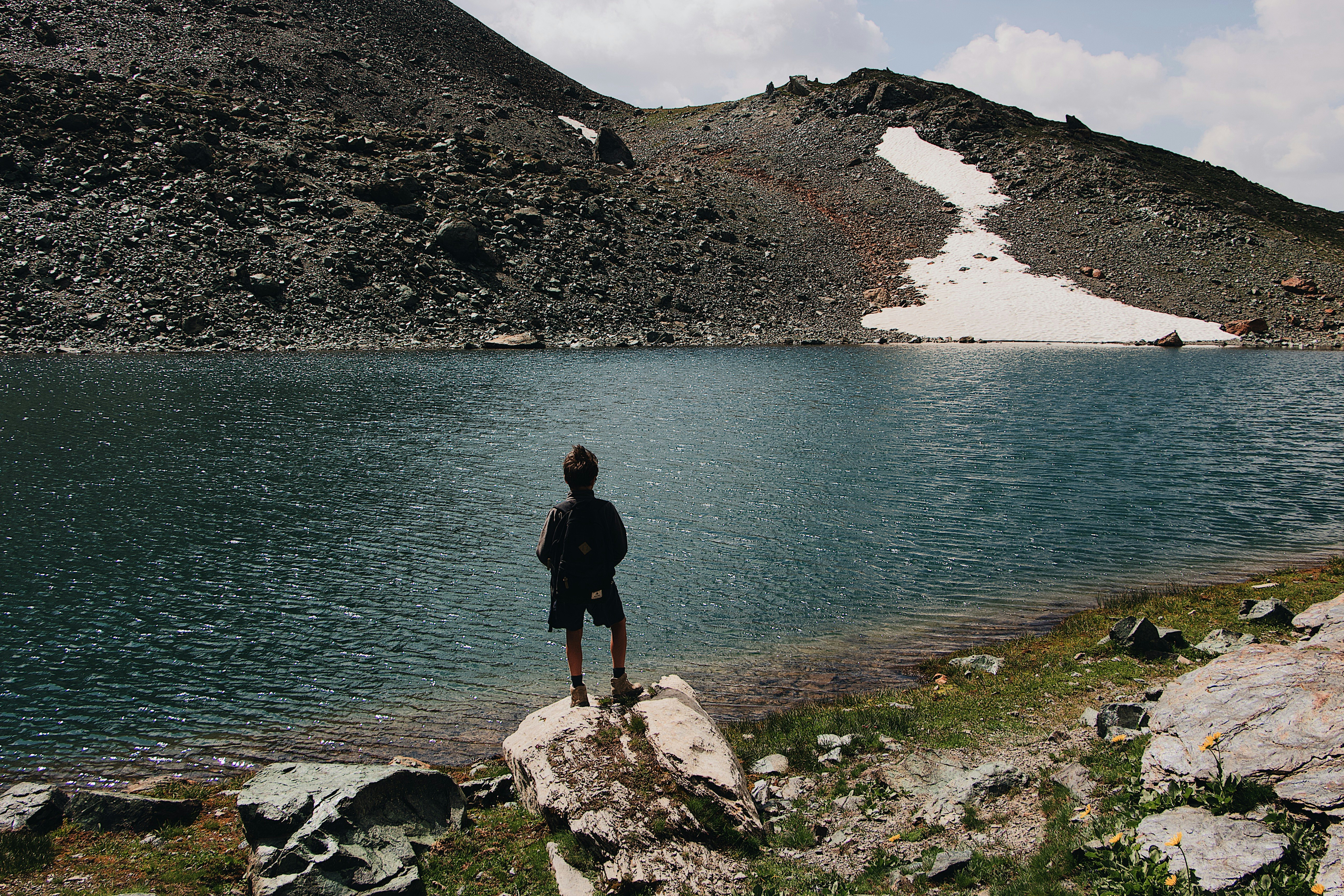 person standing on rock beside body of water during daytime