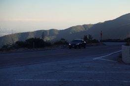 A scenic road winding through mountains with a car driving along it.