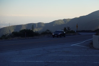 A scenic road winding through a mountainous landscape with a car driving along it.