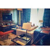 A well-lit living room with newly installed curtains and a mounted TV.