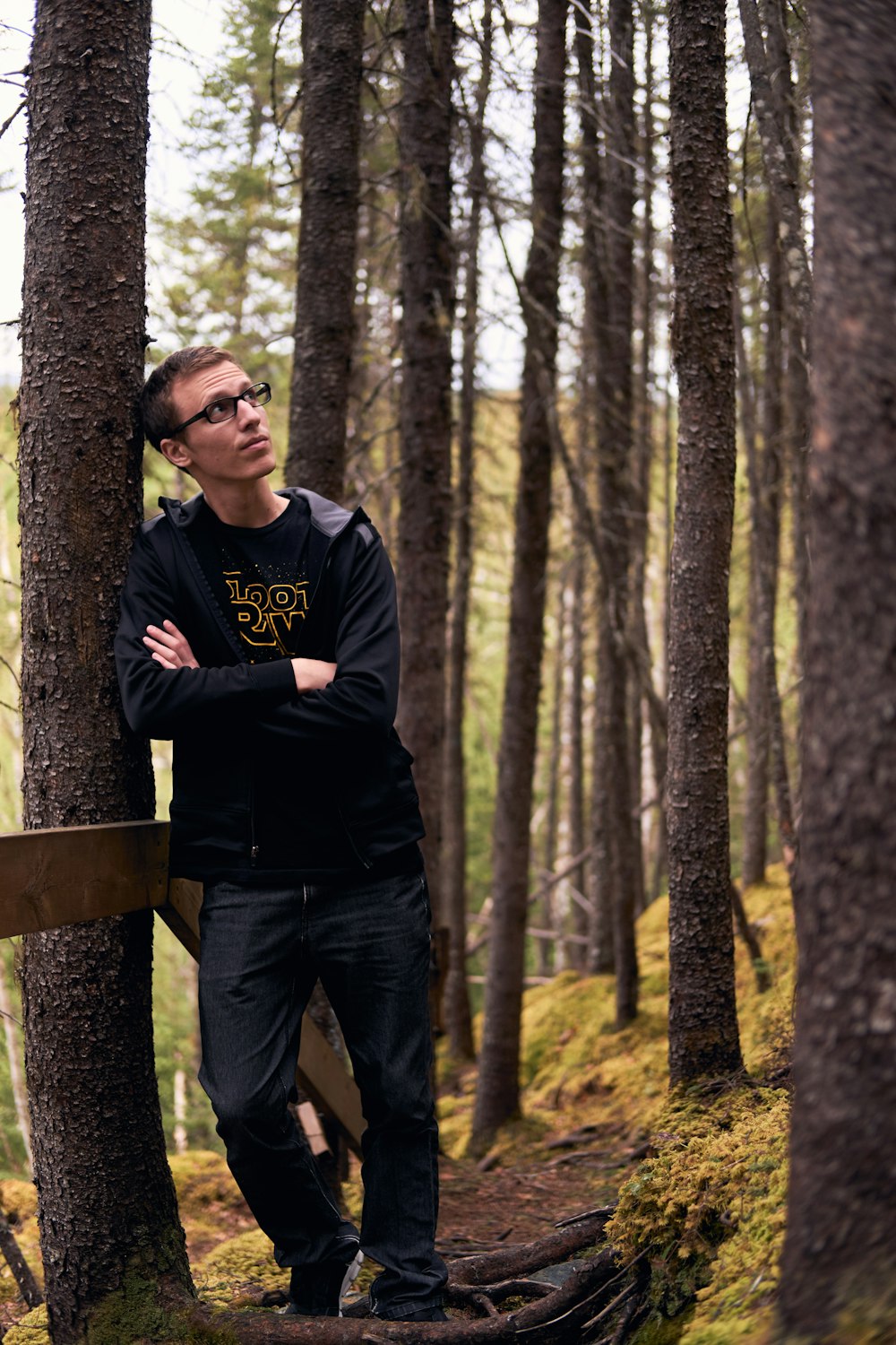 man leaninig beside tree