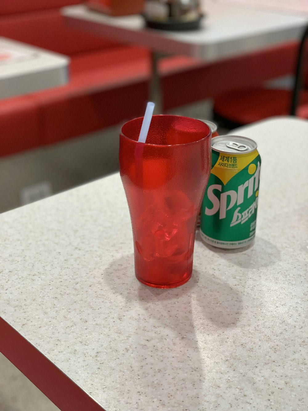 Lattina di soda Sprite accanto al bicchiere da pinta rossa