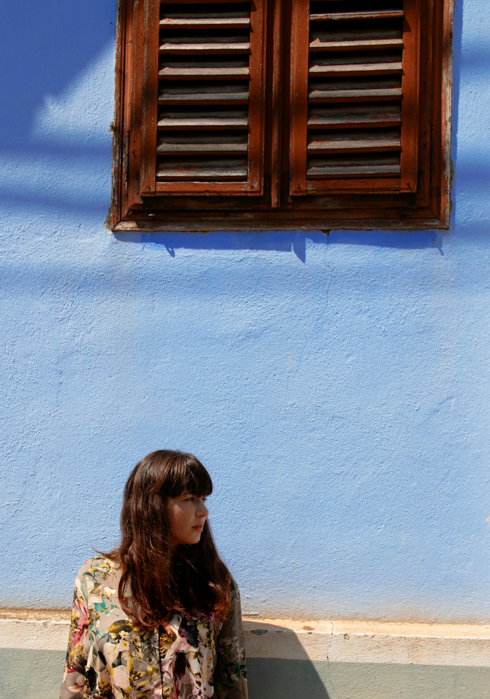 woman standing near blue painted wall and looking on her life