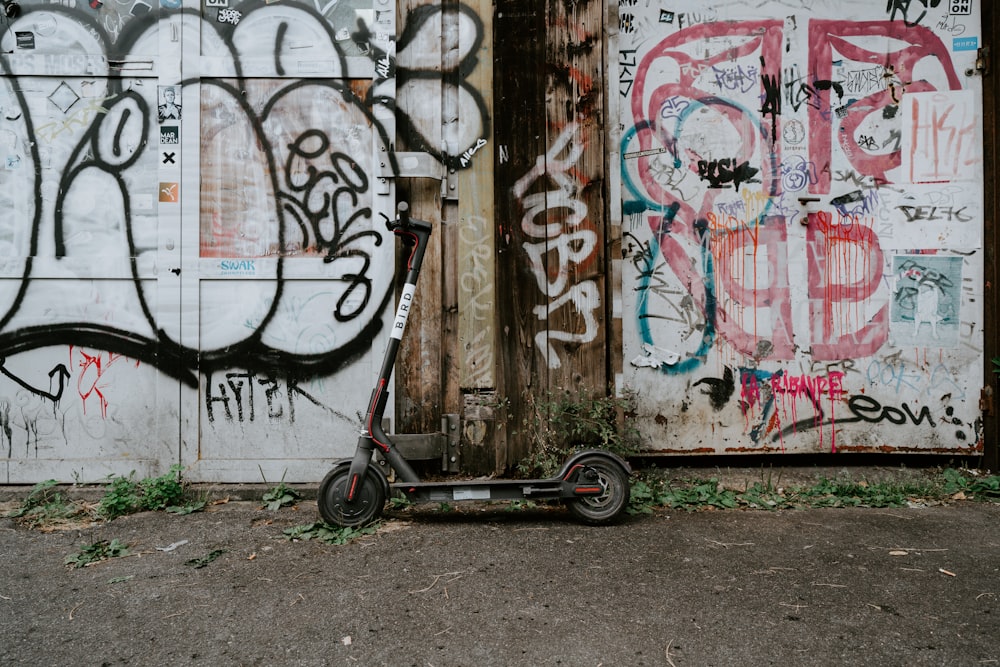 black kick scooter parked beside painted wall