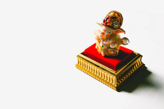 A modern designer Ganesh idol with sleek lines and a glossy finish, set against a red backdrop.