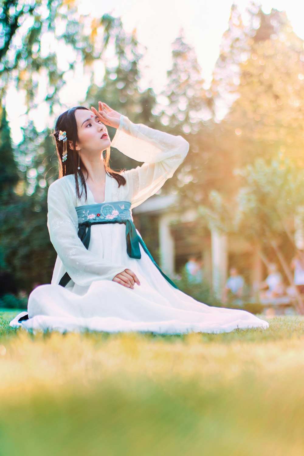 Mujer vestida de hakama blanca y azul sentada en la pradera