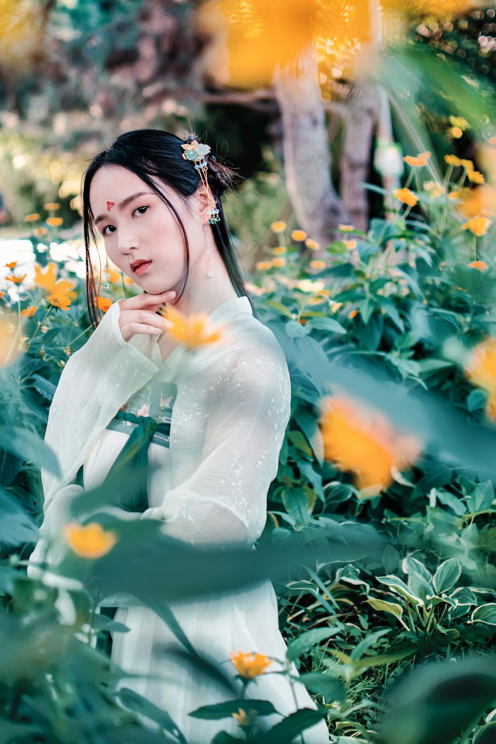 woman wearing white long-sleeved shirt behind yellow flowers during daytime