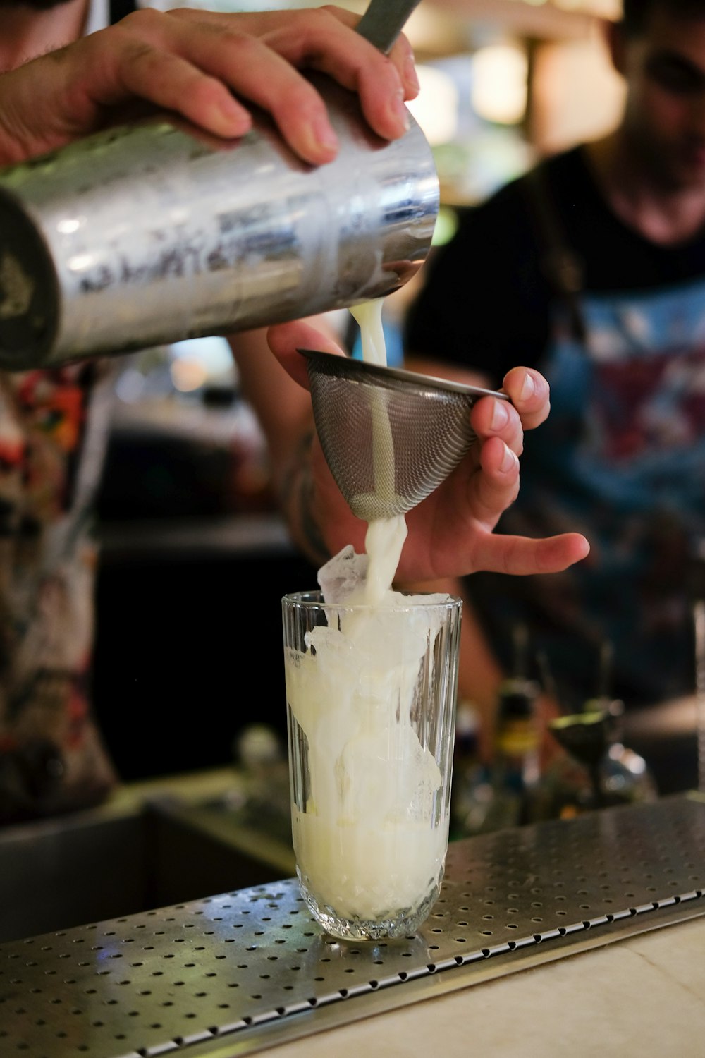 person pouring white liquid in a clear glass cup close-up photography