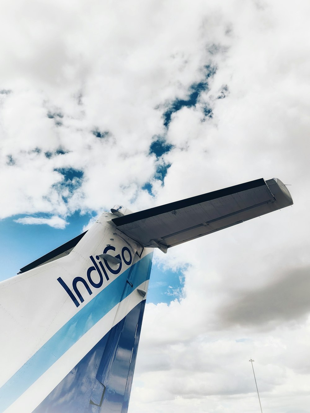 the tail end of an airplane under a cloudy sky