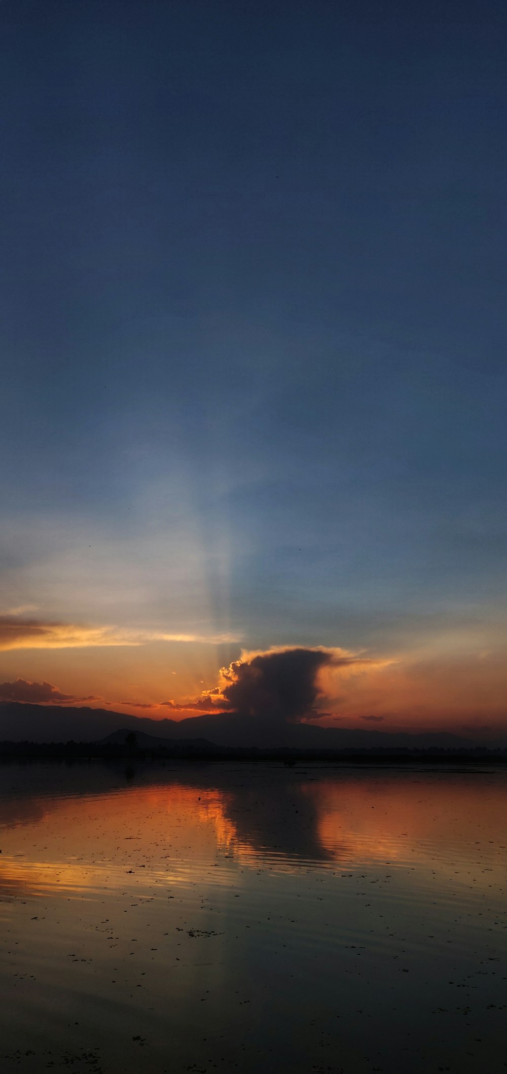 body of water across brown mountain during sunset