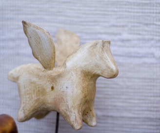 Image of a carved animal sculpture displayed on a rustic wooden shelf with natural light.
