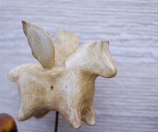 Image of a carved animal sculpture displayed on a rustic wooden shelf with natural light.