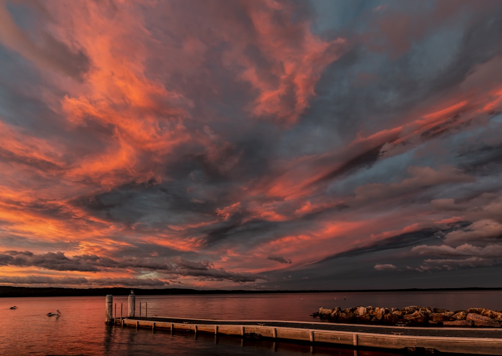 brown dock on calm body of water during golden hour