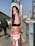 A poster of a young woman wearing a black top and white underwear with the text 'HEROIN KIDS' is wrapped around a pole on a city street. In the background, there are blurred images of people walking and urban infrastructure, including buildings and vehicles. Graffiti is visible on an electrical box nearby.