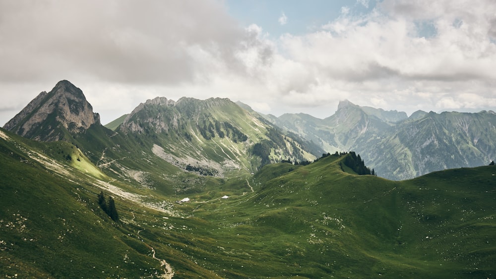 green hill near mountains during daytime