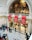 An ornate interior space with a high ceiling features intricate architectural details and a decorative, golden backdrop. Red banners with the text 'London Design Festival 2018' hang prominently. People are scattered throughout the area, walking and engaging in various activities.