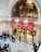 An ornate interior space with a high ceiling features intricate architectural details and a decorative, golden backdrop. Red banners with the text 'London Design Festival 2018' hang prominently. People are scattered throughout the area, walking and engaging in various activities.