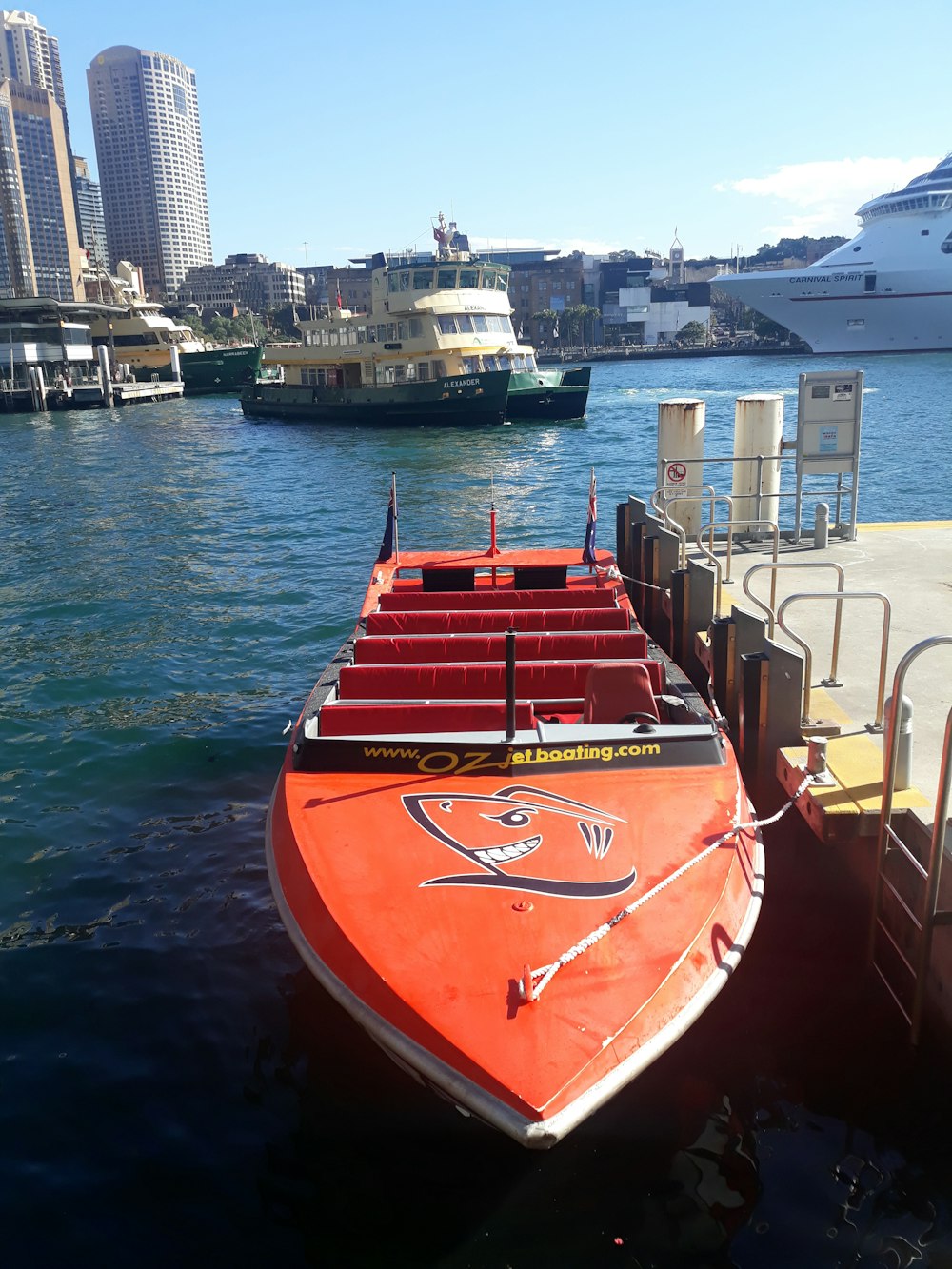 Barco a motor naranja y blanco al lado del muelle