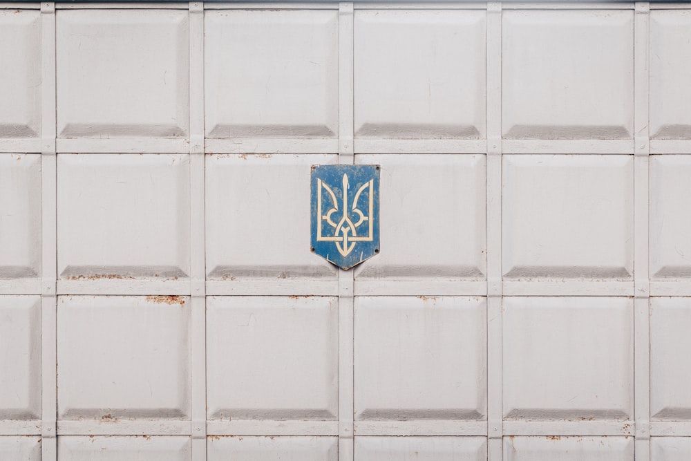 Emblema blu e bianco su parete bianca