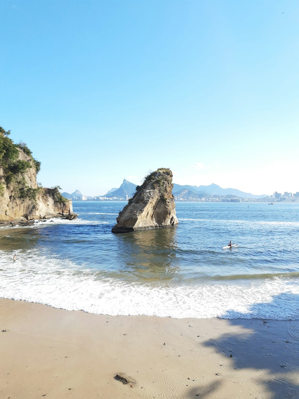 a sandy beach with a rock formation in the water