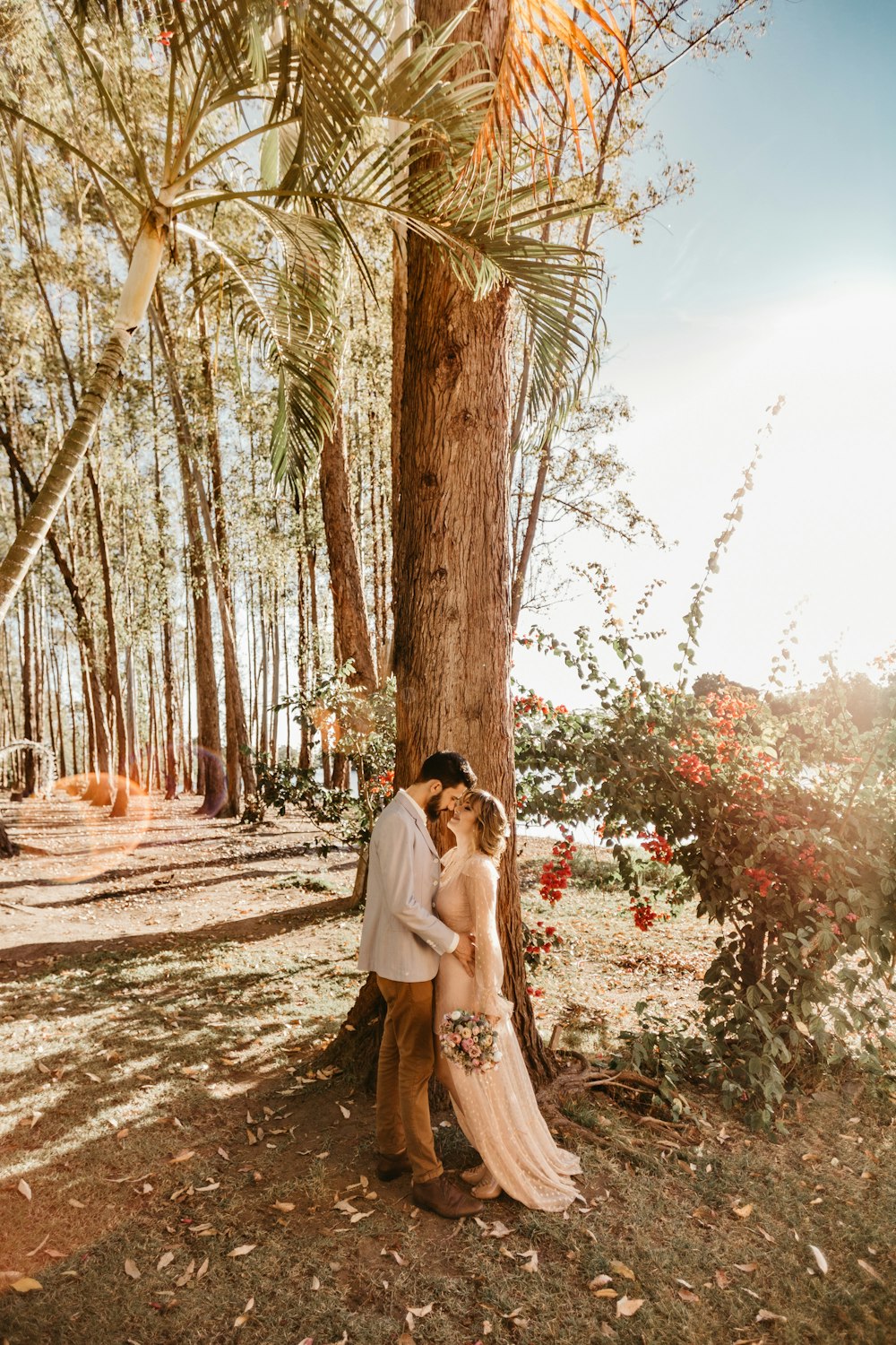 man and woman standing close and facing each other beside tall tree