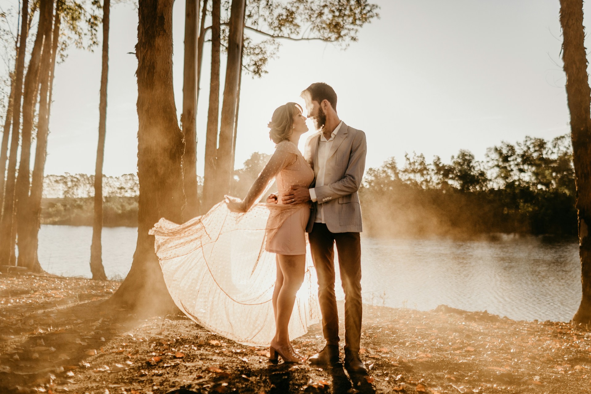 standing man and woman beside trees near body of water