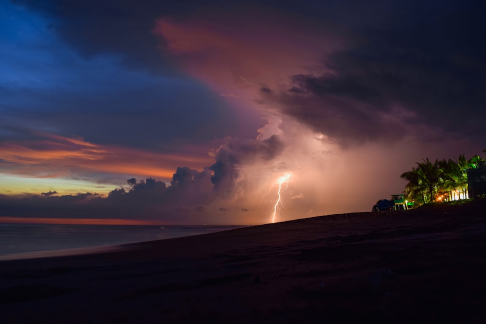 a lightning bolt is seen over a beach at night