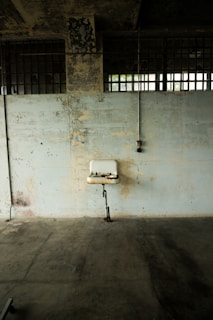 Photo of a plumber fixing a large commercial pipe under a sink in a restaurant kitchen.
