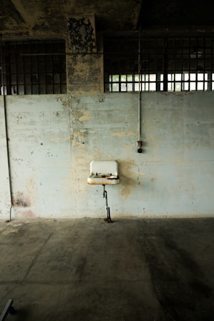 Photo of a plumber fixing a large commercial pipe under a sink in a restaurant kitchen.