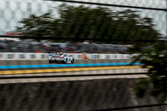 A thrilling race car speeding past the finish line with cheering fans in the background.