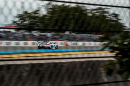 A thrilling race car speeding past the finish line with cheering fans in the background.