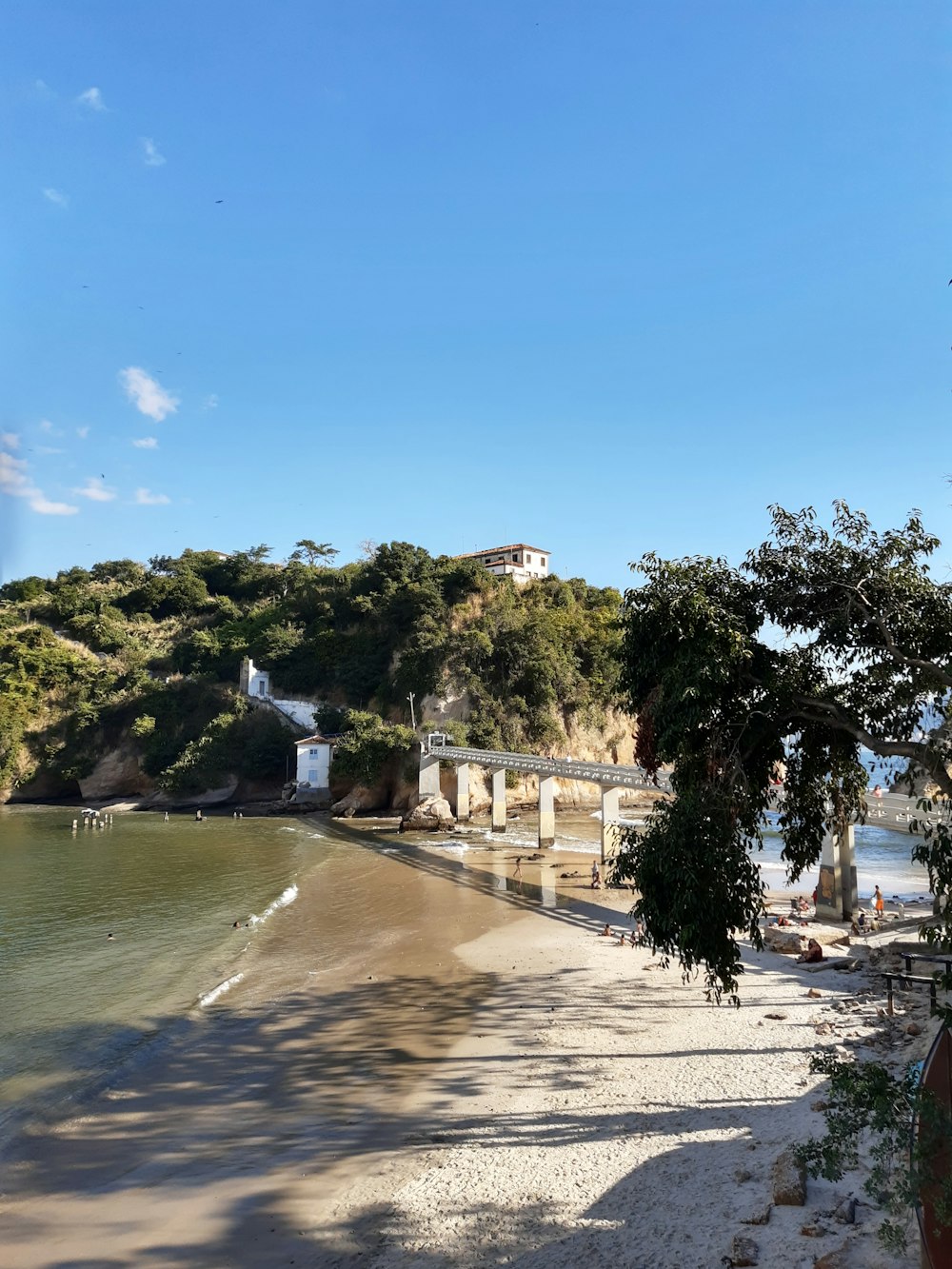 house in a hill near bridge and body of water during daytime