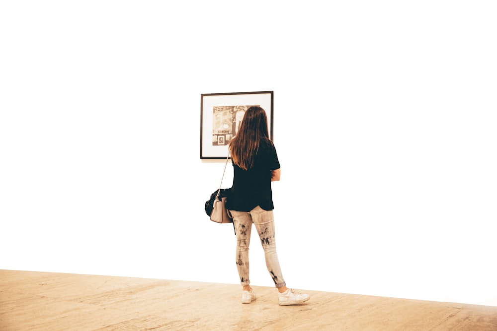 Frau im schwarzen Hemd stehend und mit Blick auf die Wand