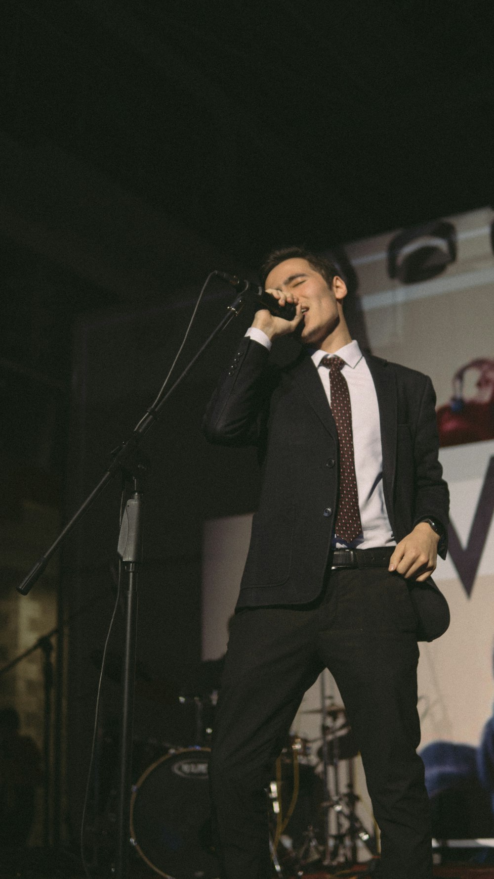 man in black suit singing on stage