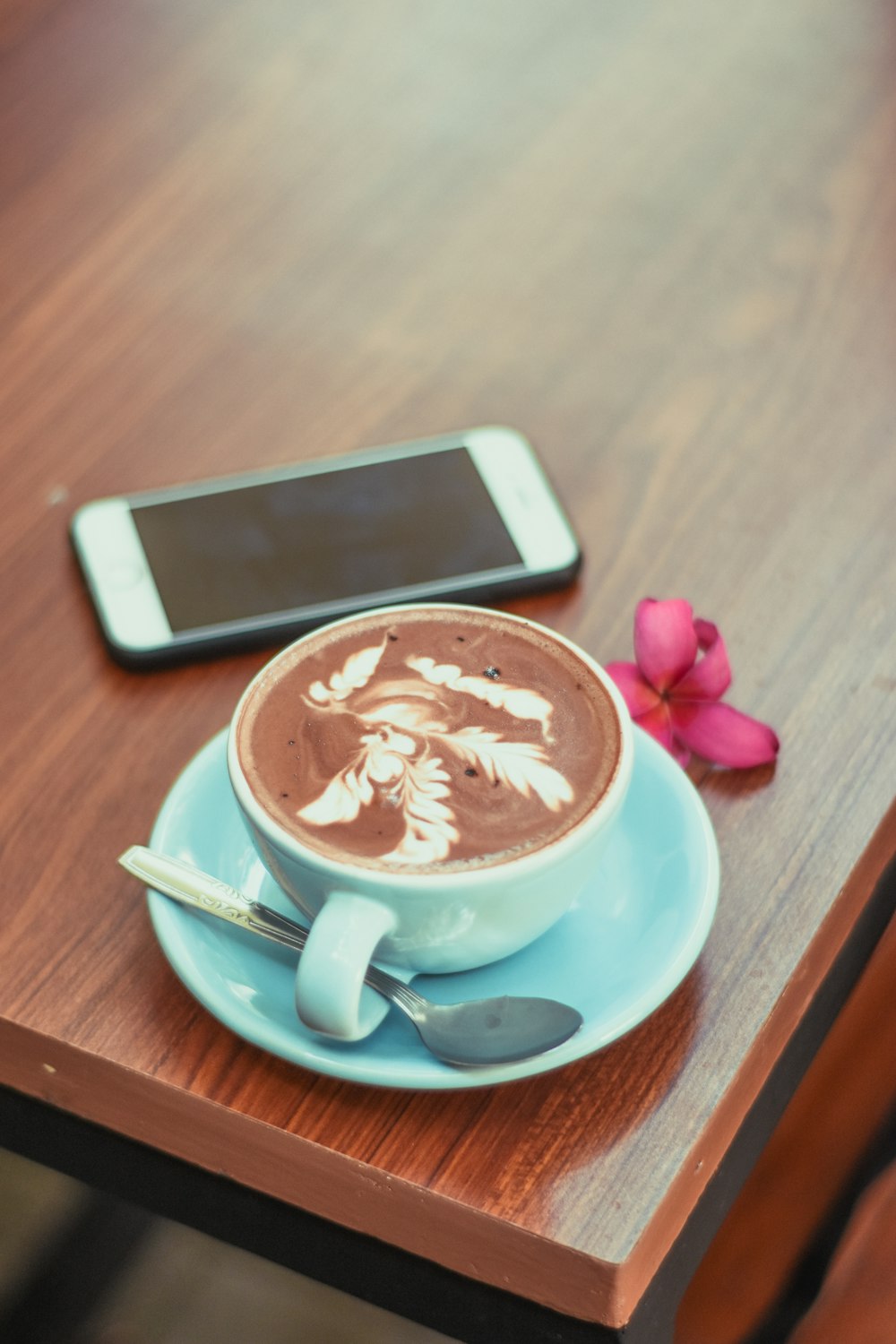 phone near a blue coffee cup with coffee and spoon close-up photography