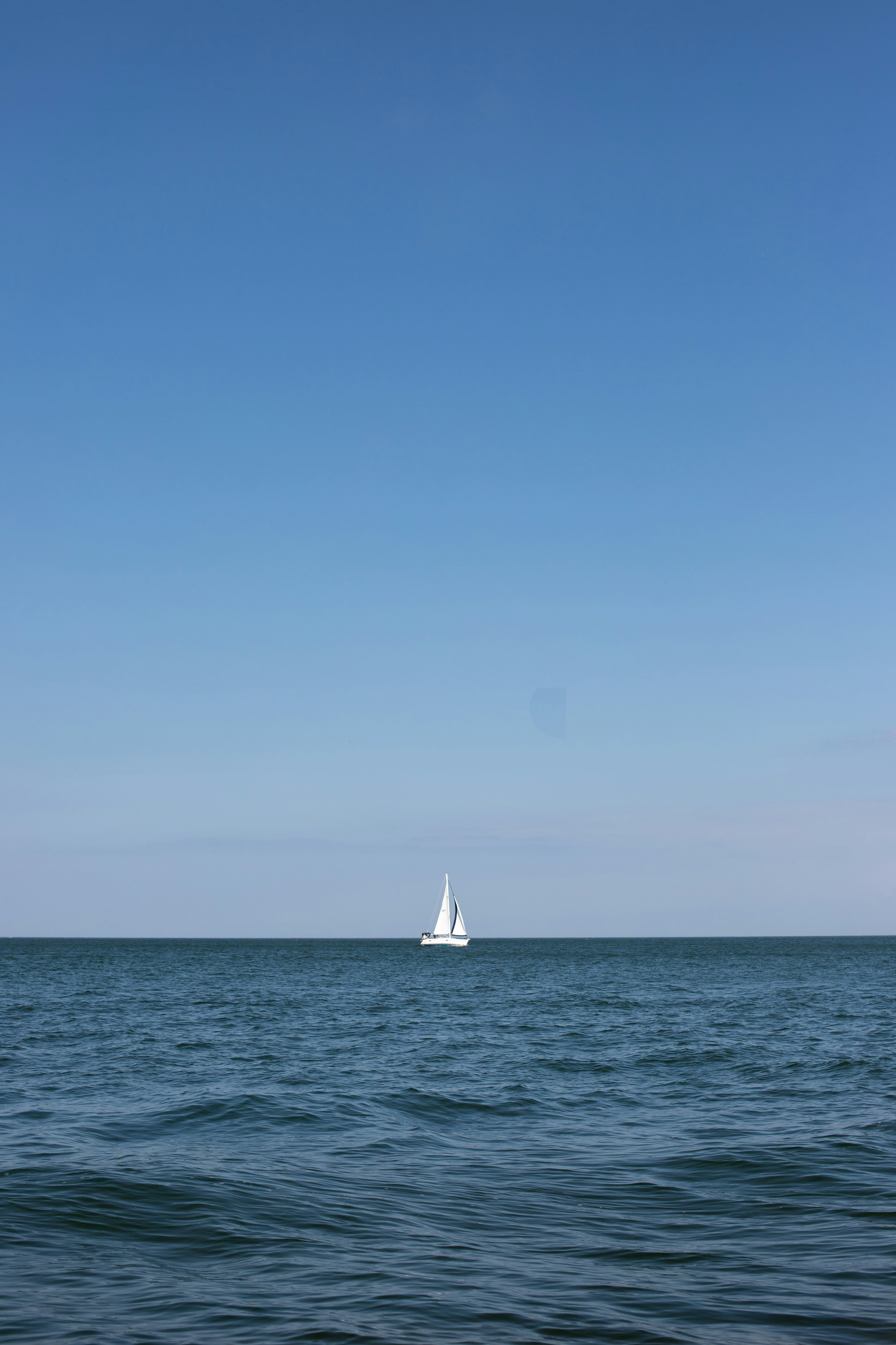 sailboat on sea under clear blue sky