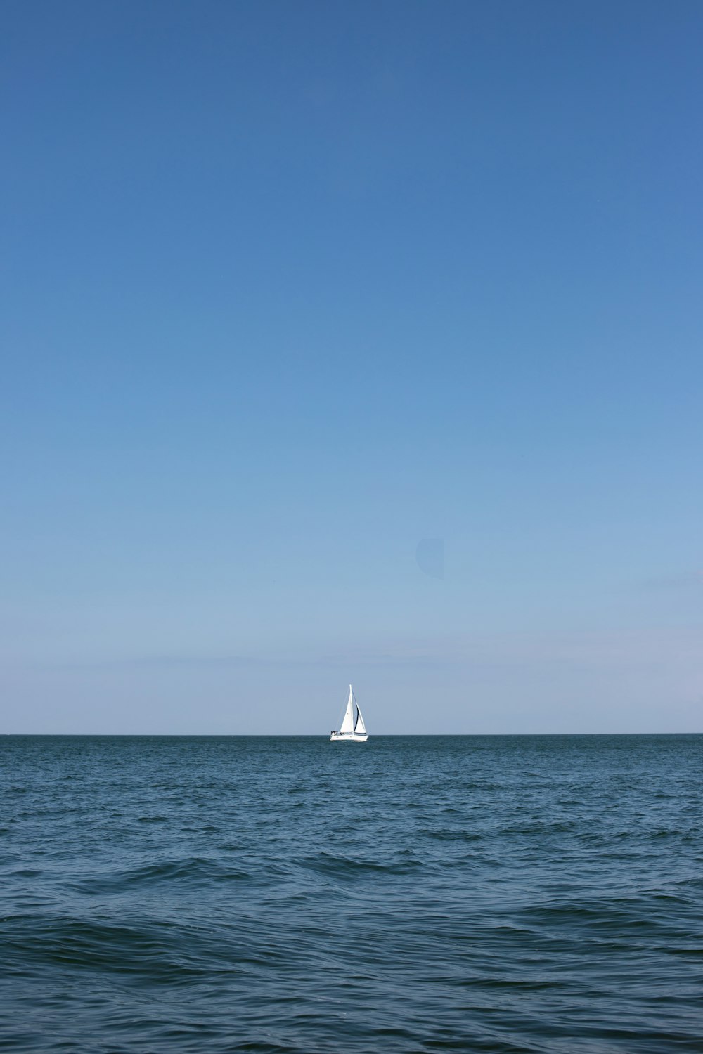 sailboat on sea under clear blue sky