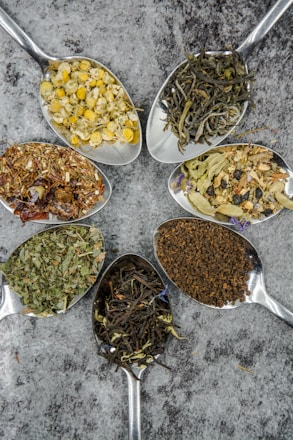 seven different spices and herbs on gray stainless steel spoons